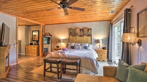 A spacious bedroom with a large bed, wooden ceiling, and a view of the outdoors. - Remodeled Crestline Retreat: Walk to Lake Gregory! (Crestline)