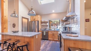 A modern kitchen with wooden cabinets, stainless steel appliances, and a central island with stools. - Large fenced yard with Hot Tub, Serene and quiet. (Carnelian Bay)