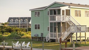 Une maison à deux étages avec un balcon et une jetée équipée de chaises.