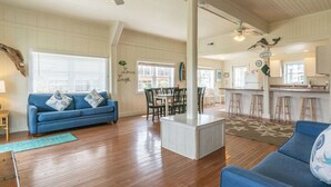 Un salon spacieux avec un canapé bleu, un plancher en bois et un coin repas comprenant des chaises et une table.