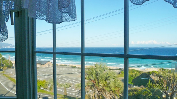 A view through a window with a view of the ocean and parking lot. - Pension A Million Roses (Shimoda)