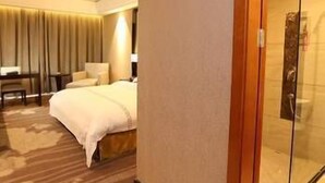 A hotel room with a bed, a desk, a chair, and a glass-enclosed shower area. - Yinhuang Holiday Hotel (Chengdu)
