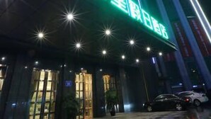 A building with illuminated signage, a visible entrance, and parked cars. - Yinhuang Holiday Hotel (Chengdu)