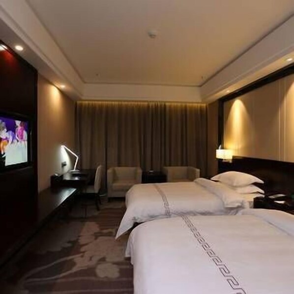 Une chambre d’hôtel avec deux lits, un bureau avec une lampe, une télévision et une chaise.