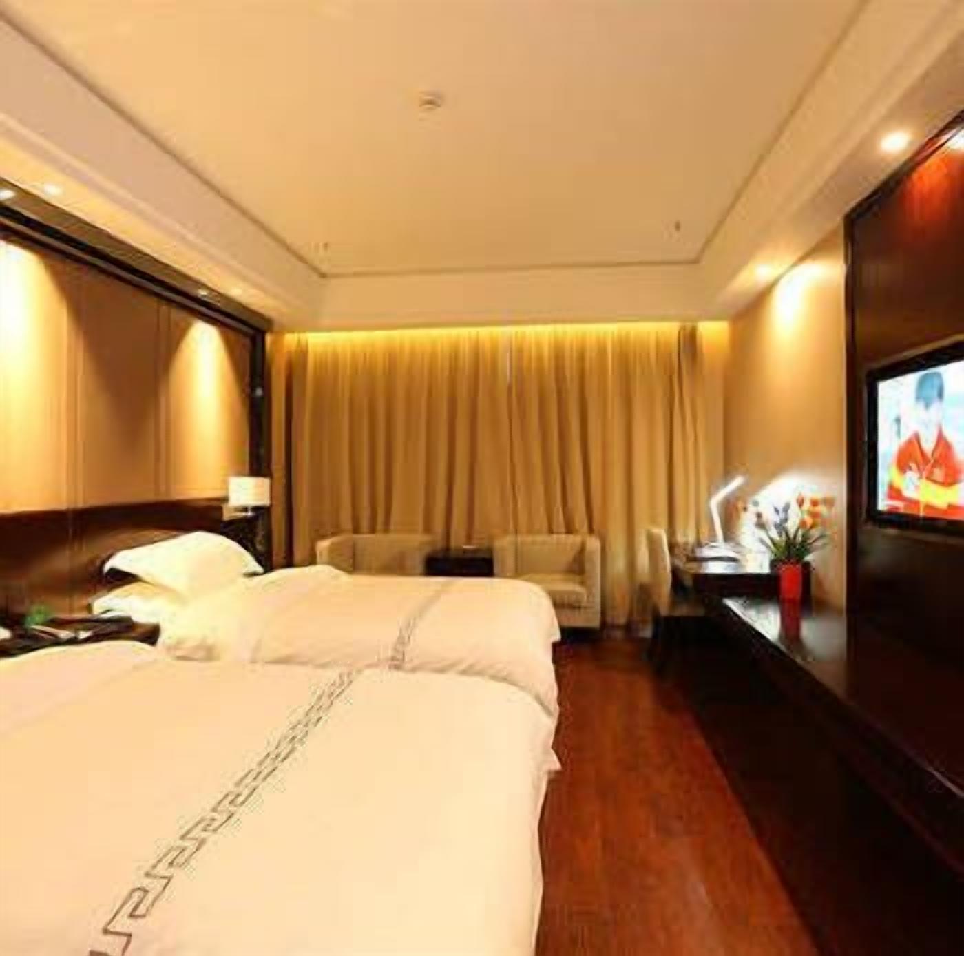Quarto de hotel com duas camas, televisão, escrivaninha e uma cadeira.
