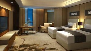 A modern hotel room with a large bed, a desk, and a chair.