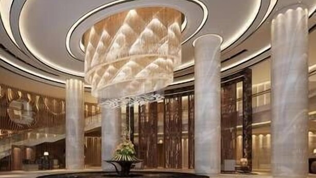 A spacious lobby with a large, central chandelier, marble columns, and a fountain.