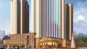 A modern hotel with a central tower and two side towers, featuring a curved facade and a large entrance.