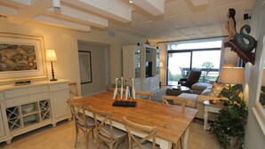 Un salon spacieux avec une table à manger en bois, des sièges confortables et une grande fenêtre donnant sur un paysage agréable.