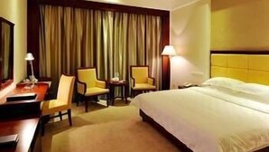 A hotel room with a bed, two armchairs, a desk, and a lamp. - Wanjiahao International Hot Spring Hotel (NanjingZhangzhou)