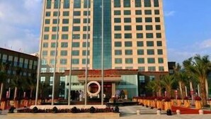A hotel with a central entrance, multiple floors, and a clear sky. - Wanjiahao International Hot Spring Hotel (NanjingZhangzhou)