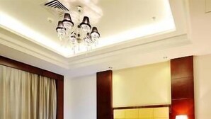 A hotel room with a large bed, a bedside table with a lamp, a sofa, and a chandelier. - Wanjiahao International Hot Spring Hotel (NanjingZhangzhou)