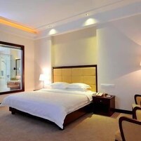 Una habitación de hotel con una cama grande, una mesita de noche con lámpara y una silla.