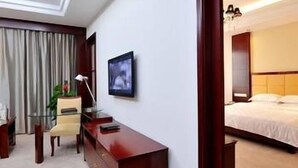 A hotel room with a desk, chair, bed, and a television on the wall. - Wanjiahao International Hot Spring Hotel (NanjingZhangzhou)