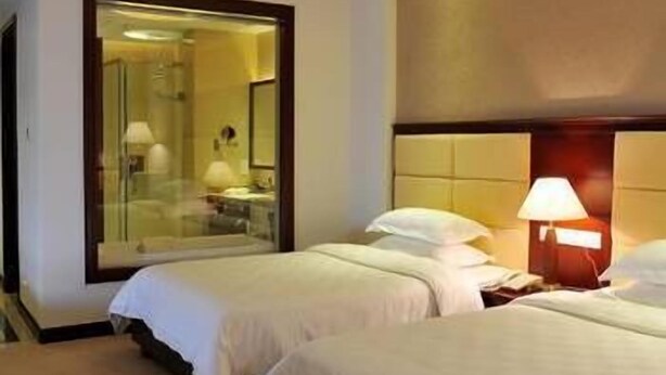 A hotel room with two beds, a large mirror, and a nightstand with a lamp. - Wanjiahao International Hot Spring Hotel (NanjingZhangzhou)