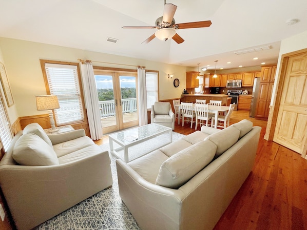 A spacious living room with a sofa, chairs, a coffee table, and a balcony with sliding doors.
