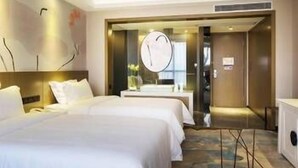 Une chambre d’hôtel avec deux lits, un grand miroir, une tête de lit en bois et une moquette à motifs.