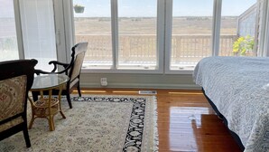 Een kamer met een bed, een tafel, twee stoelen en een groot raam met uitzicht op het landschap.