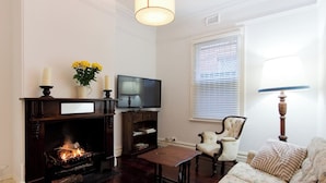 A living room with a fireplace, a television, a sofa, and a lamp.