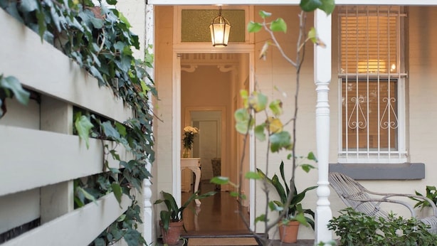 A house entrance with a wooden fence, potted plants, a bench, and a hanging lantern.