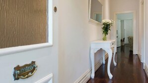 A hallway with a white console table, a mirror, and a door with a brass handle.