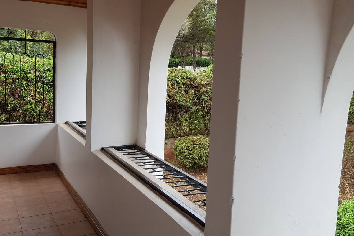 A corridor with white walls and a window with a metal grill.