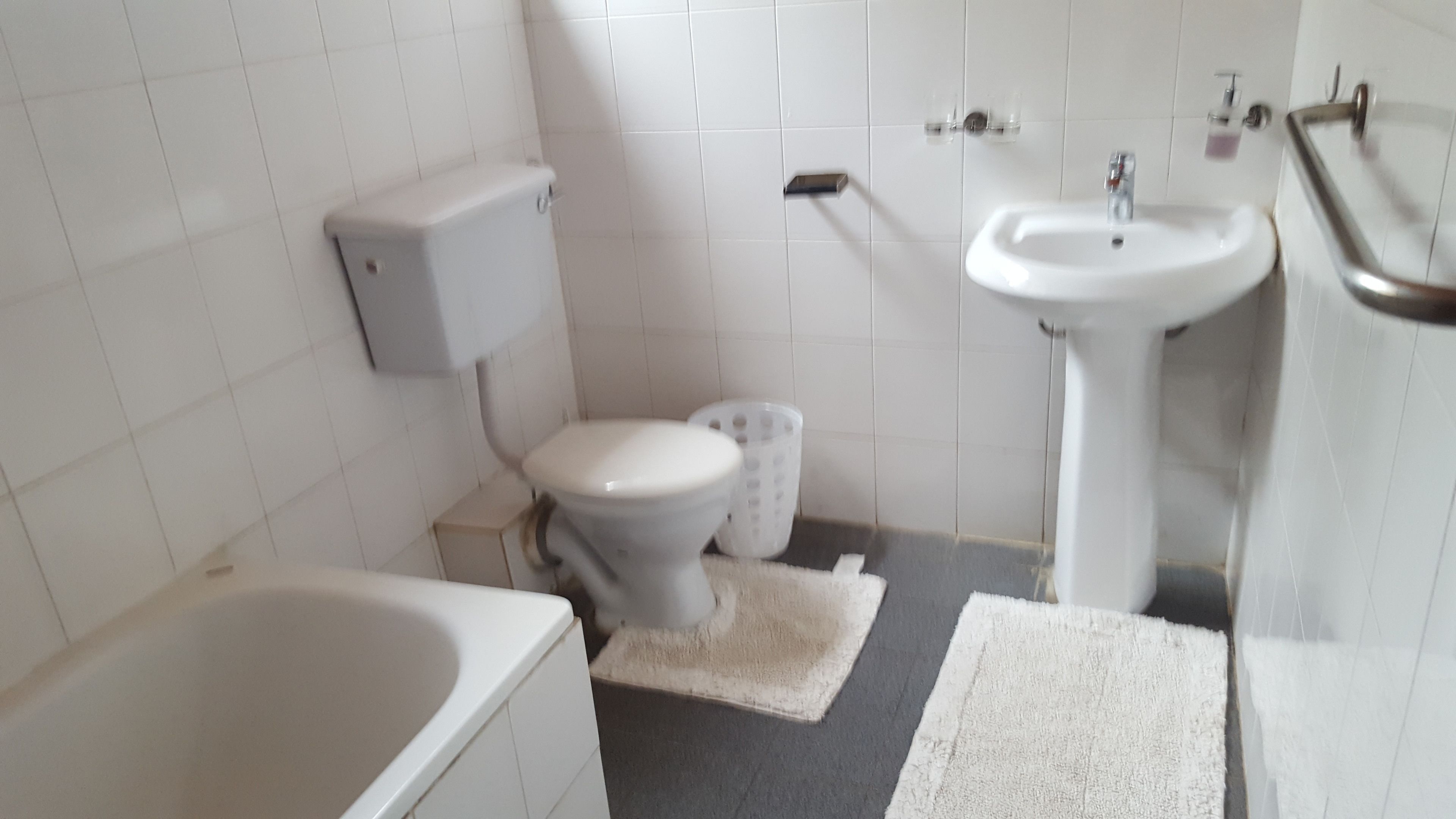 A small, clean bathroom with white fixtures, a toilet, a sink, and a bathtub.