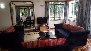 A living room with a sofa set, a television, and a dining table. - Milima 7 (Nairobi)