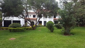 A white building with a tiled roof, surrounded by well-maintained grass and various shrubs. - Milima 7 (Nairobi)