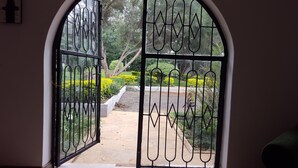 A view through a wrought iron gate leading to a garden with a paved path and various plants. - Milima 7 (Nairobi)