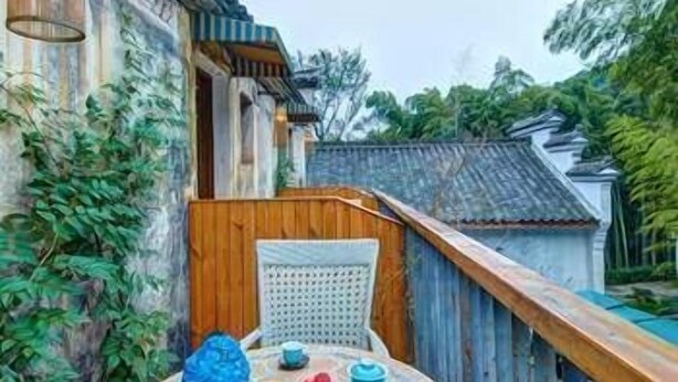 A round table with a tiled top, surrounded by a wooden fence and a building with traditional architecture. - Kaiyuan Hotel · Seabirds (Hangzhou)
