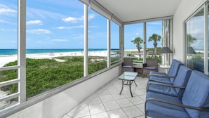 A balcony with a view of the beach, a table, chairs, and a lamp. - Island House Beach Resort 3N (Siesta Key)
