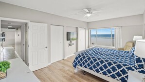 A bedroom with a bed, a ceiling fan, a TV, and a view of the beach. - Island House Beach Resort 3N (Siesta Key)