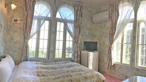 A bedroom with a bed, a TV, and a window with curtains. - Pension Smile Again (Shimoda)