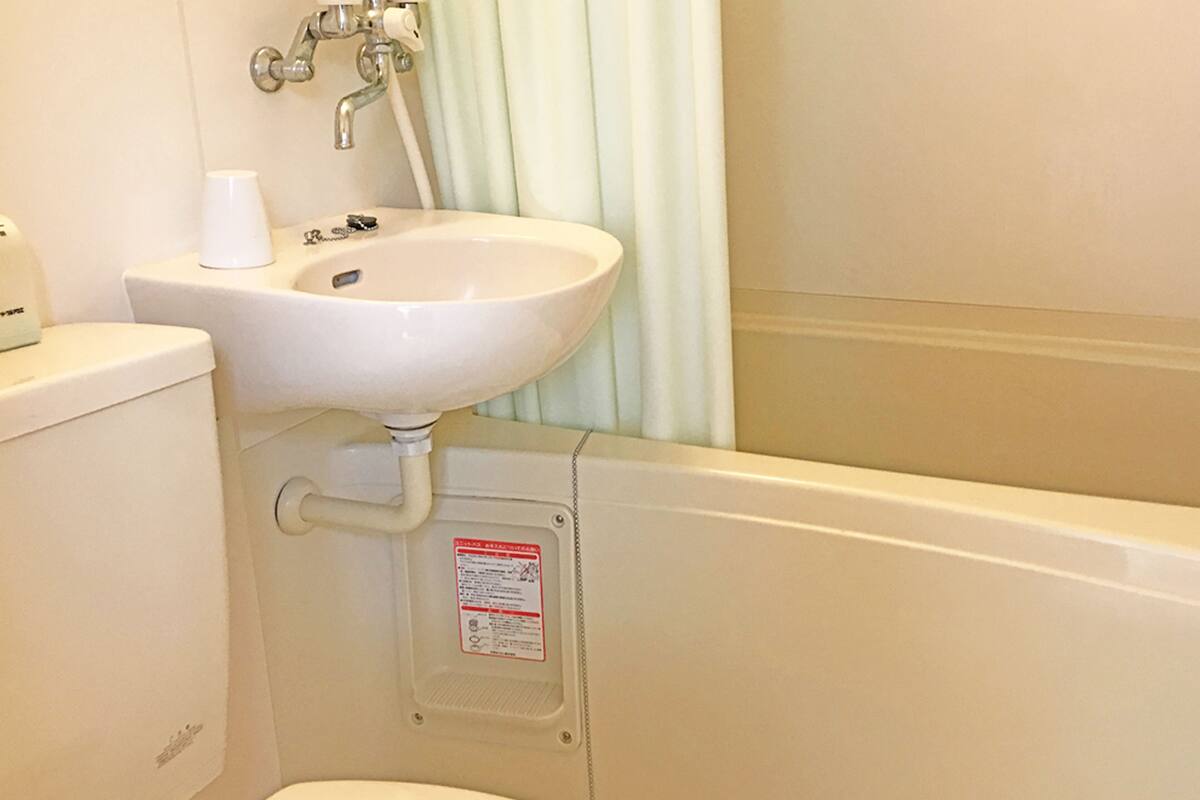 A bathroom with a toilet, sink, and shower curtain.