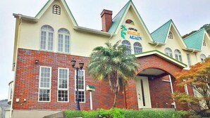 A building with a sign reading "Fenson Smile Again." It features a brick facade, multiple windows, and a green roof. - Pension Smile Again (Shimoda)