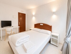 Una habitación de hotel con cama, escritorio, televisor y silla.