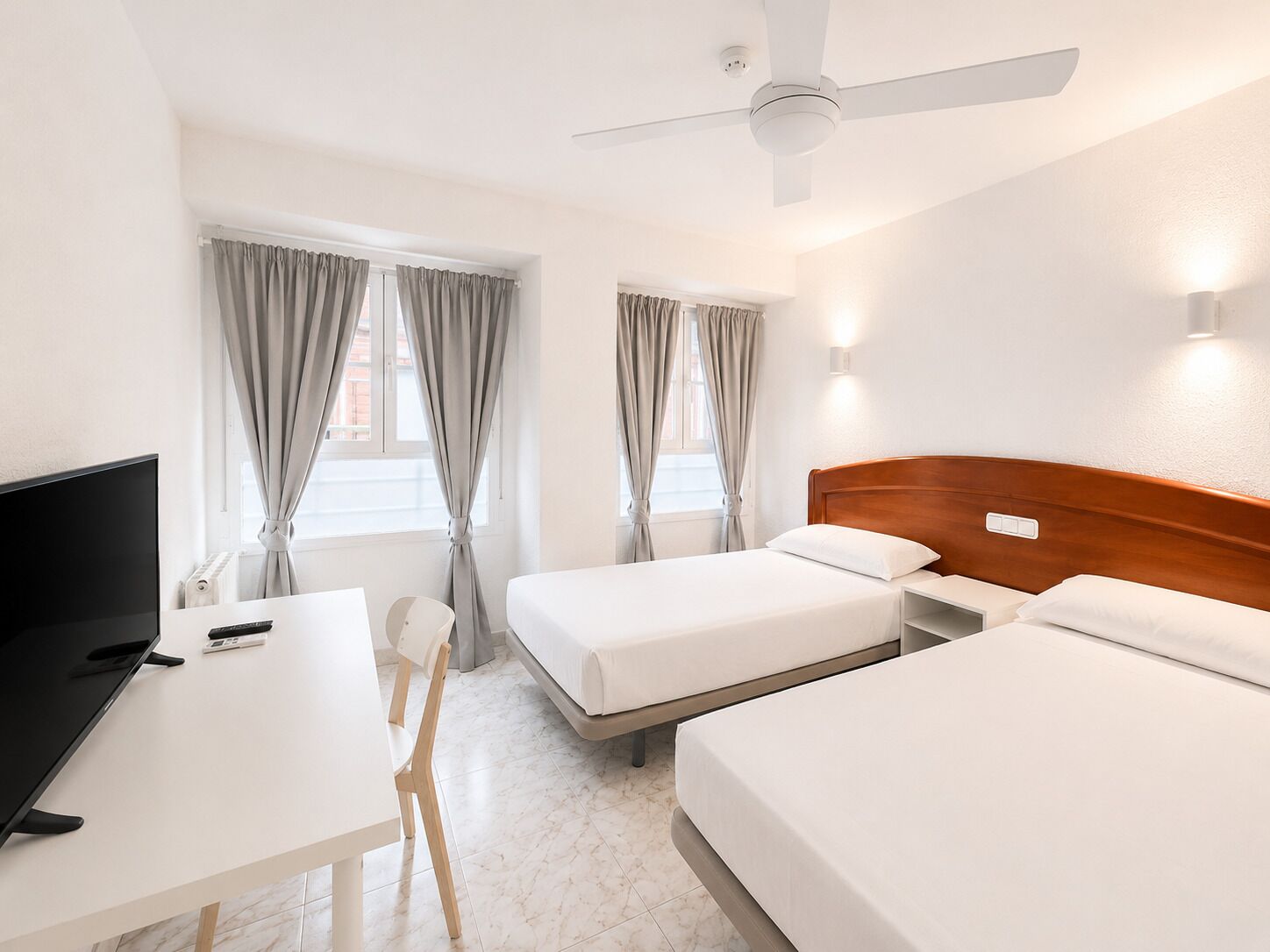 Een hotelkamer met een bed, een bureau, een stoel en een televisie.