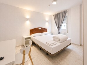 A hotel room with a bed, bedside table, chair, and a window with curtains. - Hostal La Embajada (Talavera de la Reina)