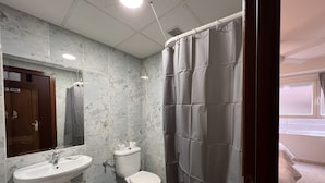 A bathroom with a sink, toilet, and shower curtain. - Hostal La Embajada (Talavera de la Reina)