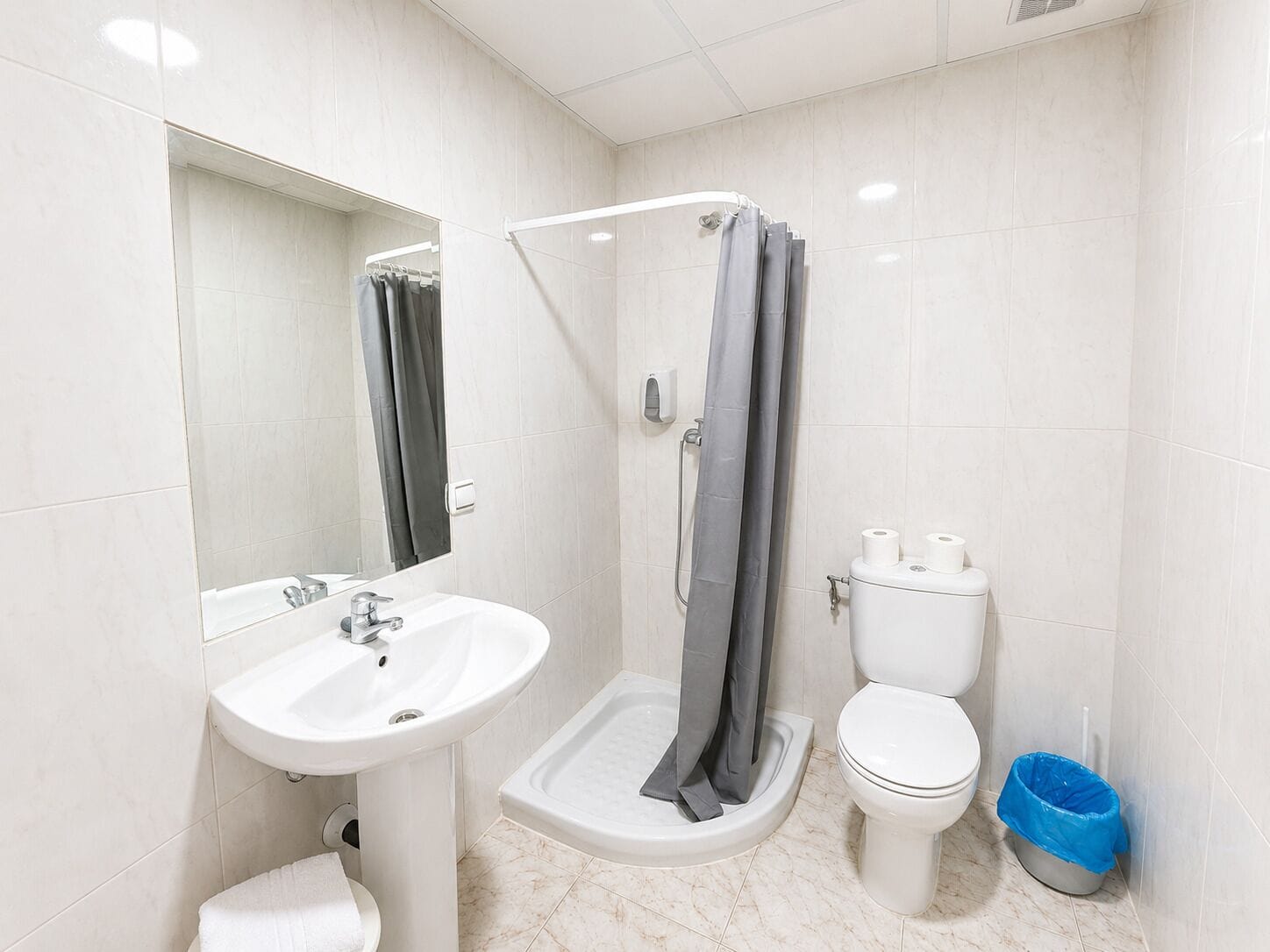 Een moderne badkamer met een wastafel, toilet, douche en een spiegel.