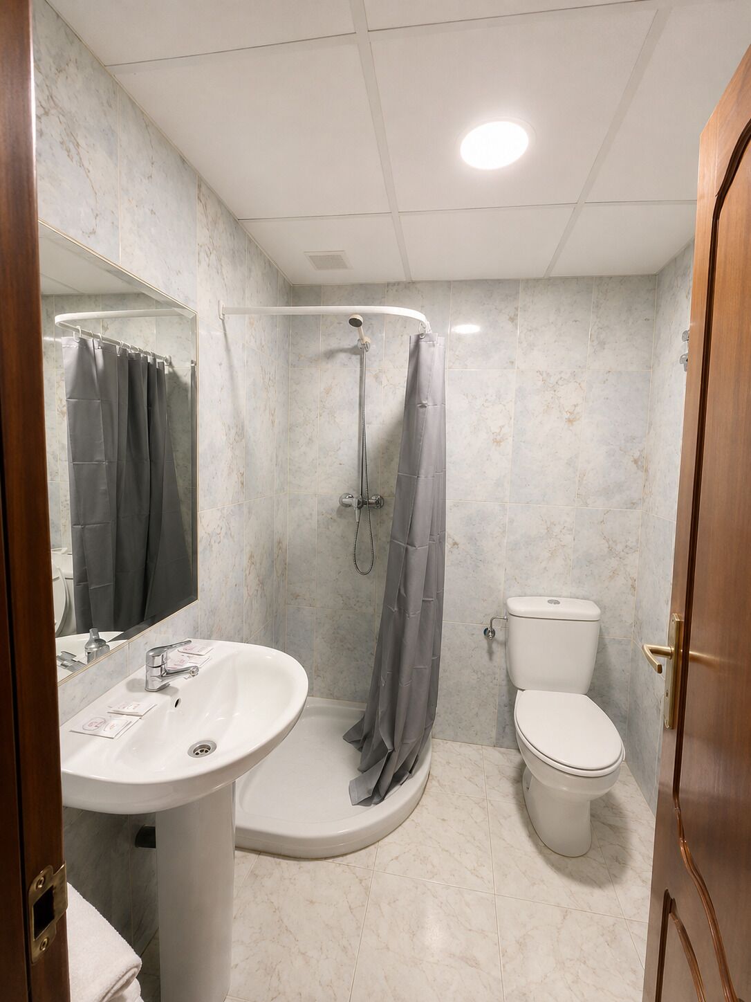 Une salle de bain avec douche, toilettes et lavabo.