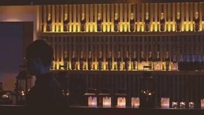 Uma área de bar com uma placa de neon e uma fileira de garrafas.