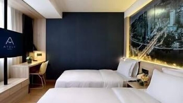 Quarto de hotel com duas camas, uma mesa e uma grande pintura da paisagem urbana na parede.