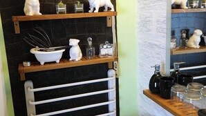 A bathroom with a black tiled wall, a white sink, and shelves with toiletries.
