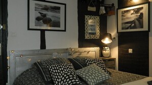 A bedroom with a bed, patterned pillows, a nightstand with a lamp, and framed pictures on the wall.