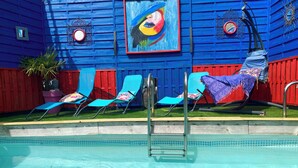 A pool area with blue chairs and a ladder.