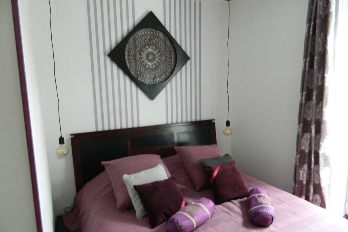 A neatly made bed with multiple pillows and a decorative wall hanging.