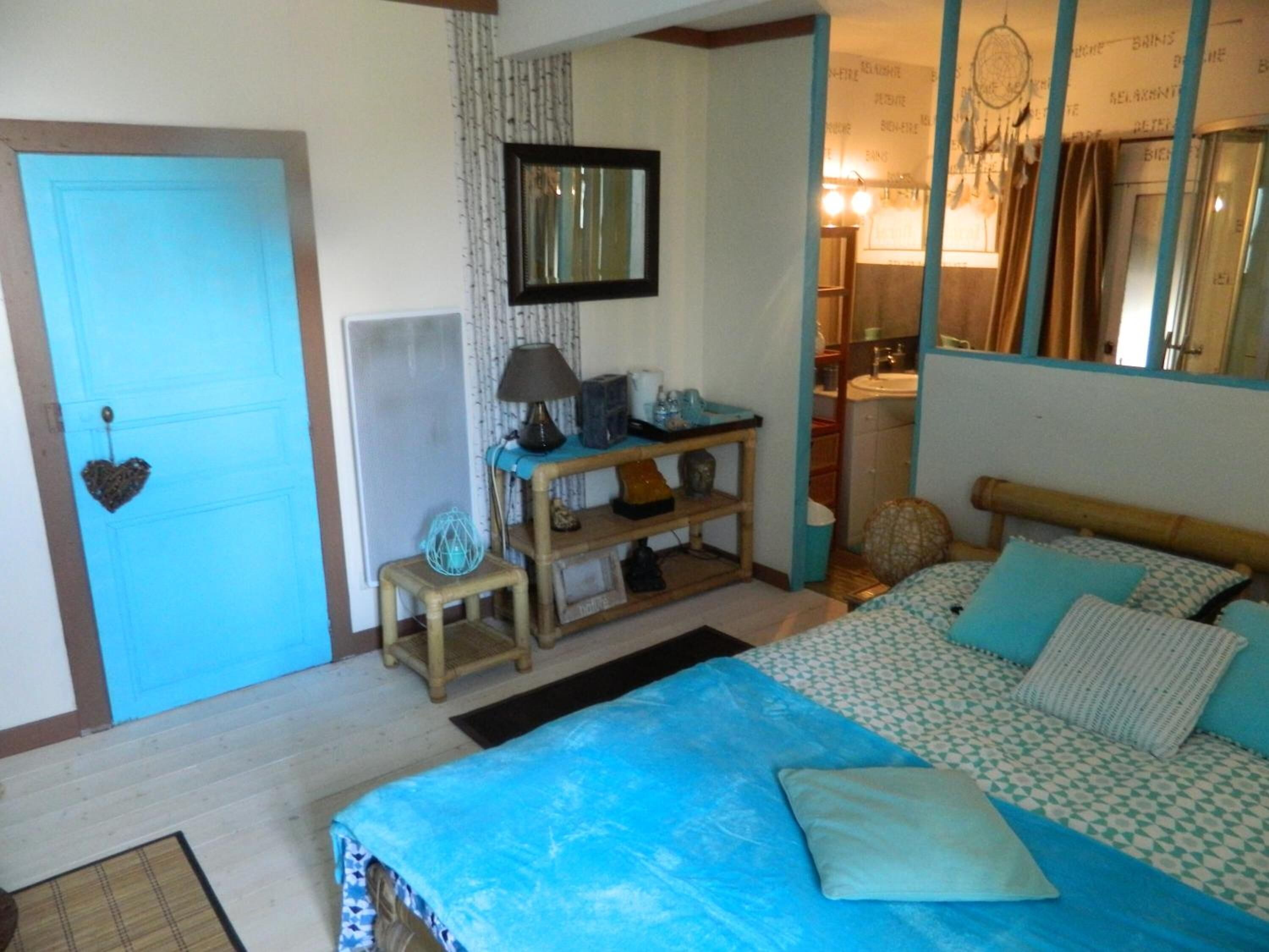Un dormitorio con cama, mesita de noche, espejo y un pequeño taburete.