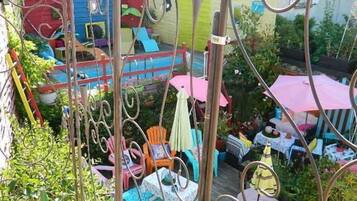A colorful outdoor area with various seating arrangements, including chairs and tables, surrounded by plants and decorative elements.
